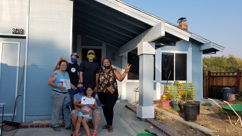 Jocelyn (right) poses in front of her newly painted house.