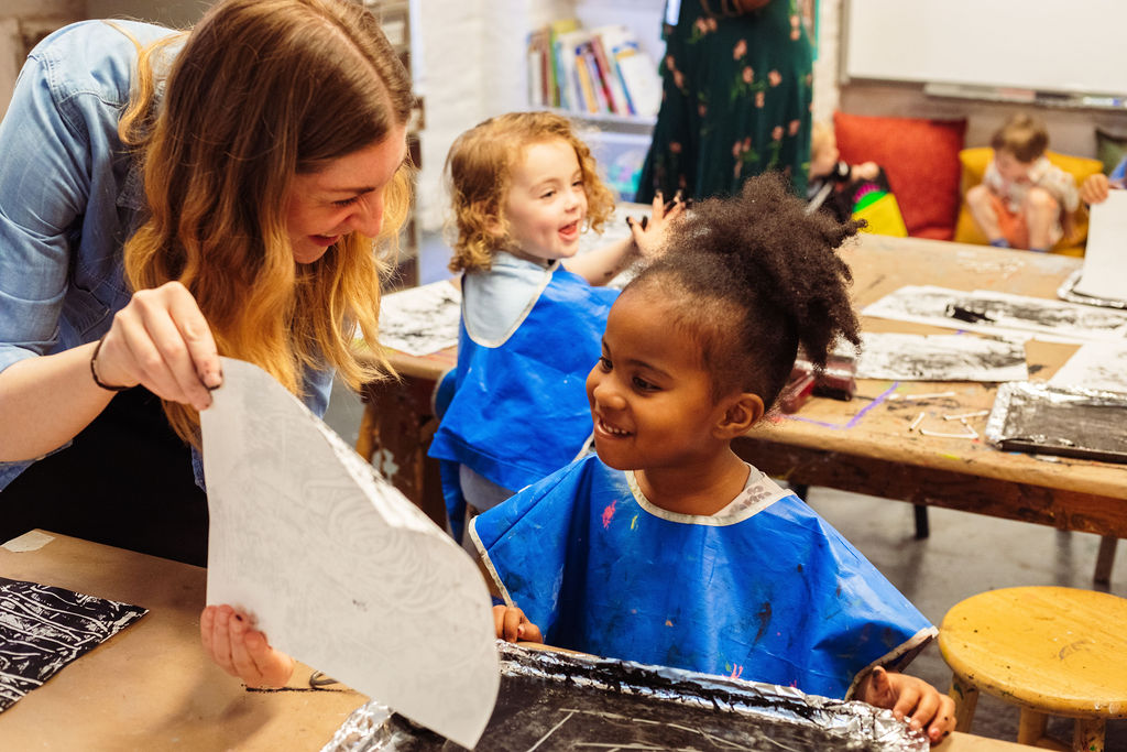 A Corlears School student from the Seedlings nursery program sharing their art with the Studio Art teacher