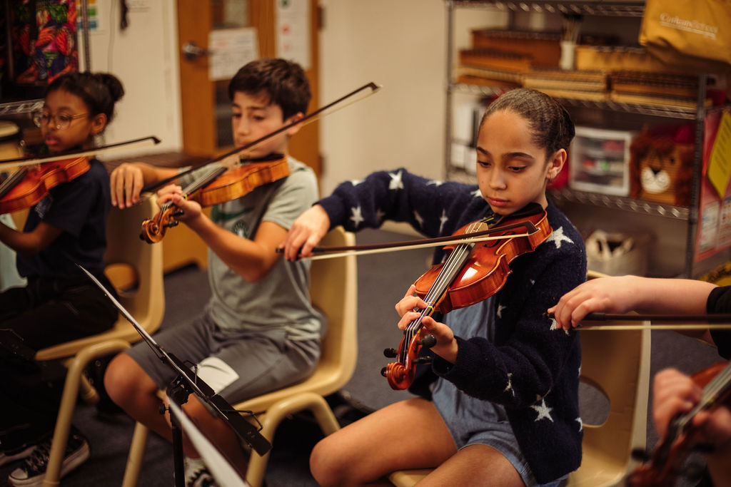 Corlears School fifth graders practicing violin in music class